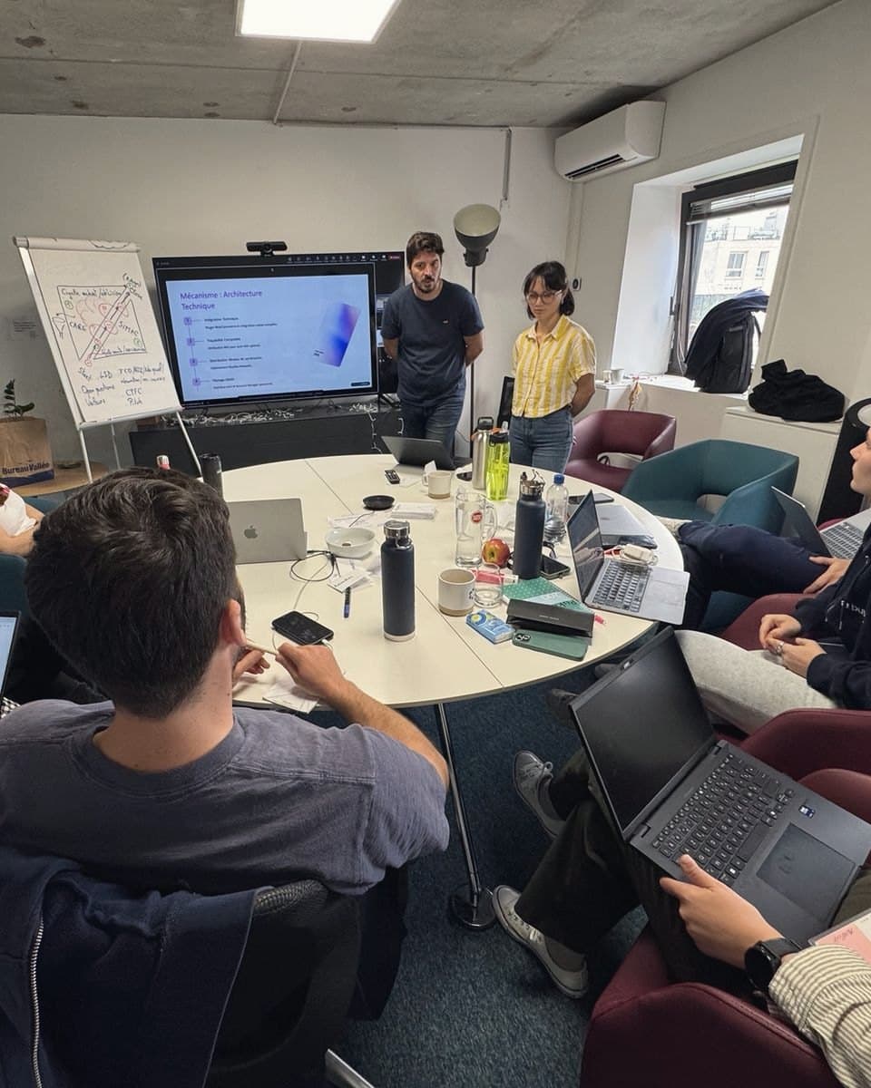 A sales team around a round table: two colleagues present their work on the screen.